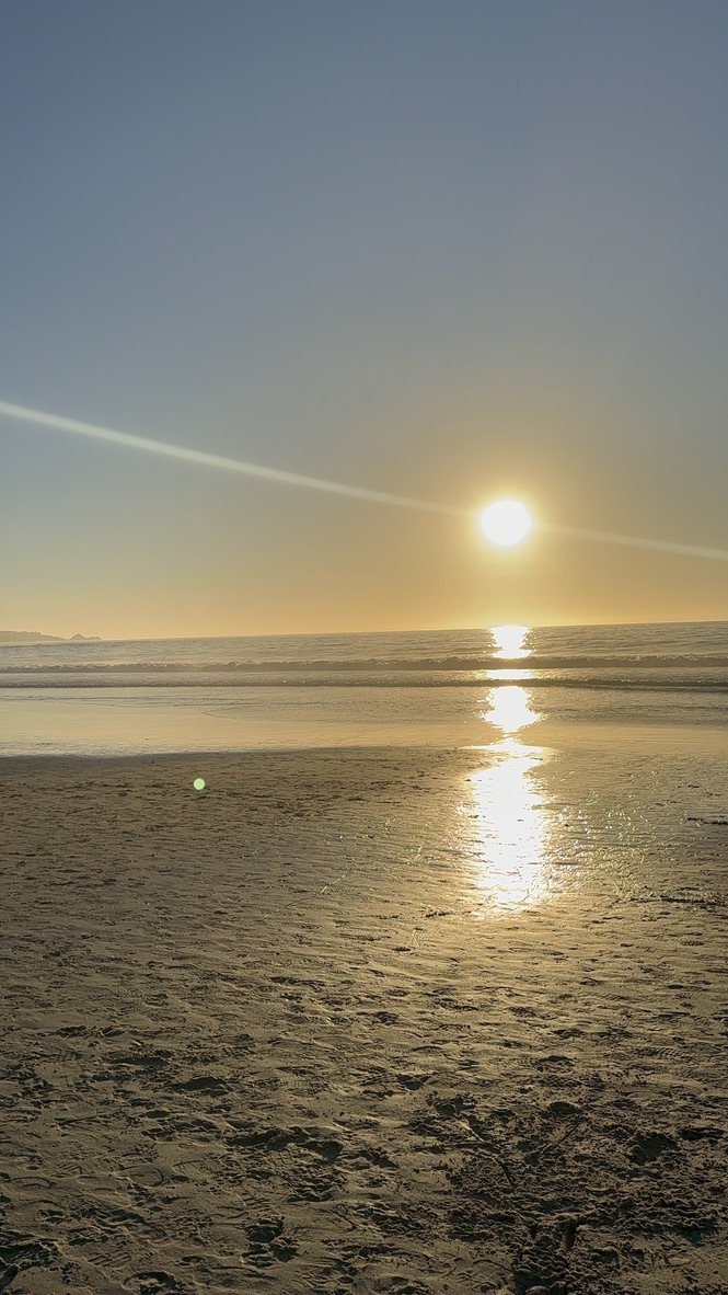 Sun setting over the Pacific Ocean, gold reflection on wet sand